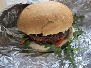 Vegan burger "Brezmesni kralj" with potato bombette, soy patty, barbecue sauce, fried onion, arugula, tomato, vegan cheddar cheese.  at Bullizza in Ljubljana