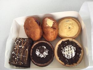 Clockwise from back - Chocolate mud cake brownie, jam doughnut, custard doughnut, passion fruit custard tart, caramel tart and chocolate tart. All delicious! at Flour of Life Bakery in Helensvale