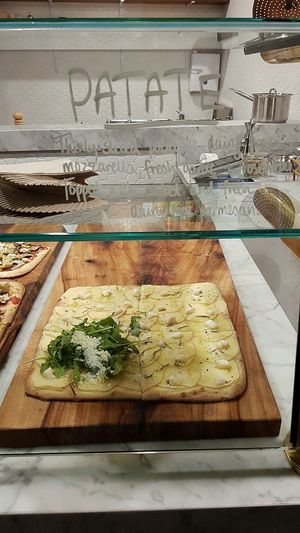 Patate pizza with Thinly- sliced potatoes, dairy-free mozzarella, fresh garlic + rosemary. Topped with rocket and fresh dairy-free parmesan at By GiGi in Miami
