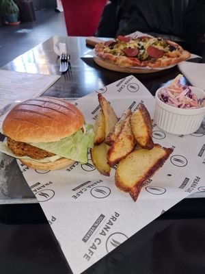 Spicy bean burger with wedges & coleslaw. Top of photo is a personalised pizza at Prana Cafe in Leicester