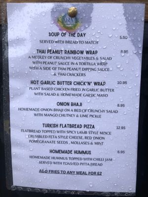 Menu as of July 2024 (seen from outside on a rainy summer day!) at Karmic Cakery in Berwick-upon-tweed