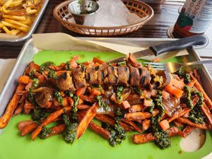 Veggie apple sausage over sweet potatoes with caramelized onions, diced tomatoes, and chimichurri at Bangers & Brews in Bend