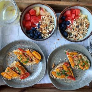 Sourdough slices with hummus, roasted pumpkin with ras-el-hanout, parsley, heirloom tomatoes & dukkah. Soy & coconut yogurt, peach, blueberries & homemade granola. Ginger infusion at Vegan B&B Valkenbos in The Hague