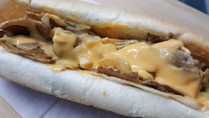 Philly Cheesesteak - House-made "meat" seasoned right, with fried onions, our famous cheese whiz and philly steak rolls.   at Dina's Vegan Deli & Desserts in West Palm Beach