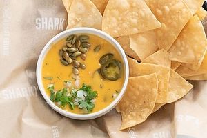 Queso & Chips 100% Plant-based Queso, with jalapeños, pepitas, onion and cilantro topping it off. at Sharky's Woodfired Mexican Grill in Sherman Oaks