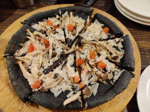 I order the mushroom and garlic pizza with soy cheese. The crust was colored with bamboo charcoal which adds gut health benefits at Volver in Kochi