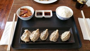 Dumplings with sauce and sides at Lucky Dumpling in Zurich