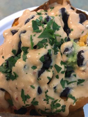 Baked sweet potato stuffed with avocado and black beans, topped with tahini-harissa sauce. at Sealantro in Vero Beach