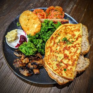 Chickpea "Omelette" with kale, roasted tomatoes, sauteed mushrooms, vegan sausage, and a hash brown pattie at Gorilla Kitchen in Auckland