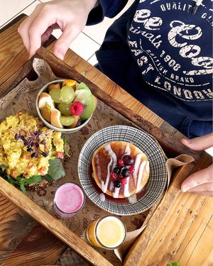 Brunch board: smashed avo or 'egg' mayo chickpeas on toast, a mini stack of berry pancakes, a bowl of fresh fruit, a shot of fresh orange juice, a shot of berry smoothie at Meraki Market Cafe in Paphos