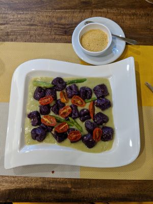 Purple potato gnocchi with asparagus coulis and sun-dried tomatoes. Vegan parmesan to sprinkle on the side at Buon Gusto in Phuket