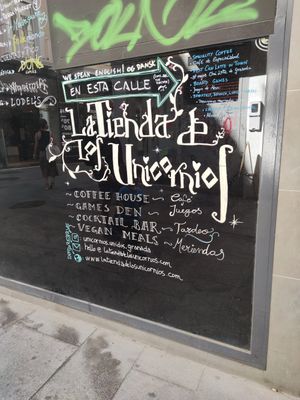 Sign on busier street showing restaurant directions at La Tienda de Los Unicornios in Granada