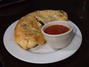 Calzone with black olives, vegan chicken, and ricotta with a side of sauce at Ethos Vegan Kitchen in Winter Park