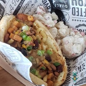 Field Roast Frankenfurter split and grilled served on a toasted bun & loaded with Chili & Cheese -Shown served with stuffed redskin potato salad.  at Bumbling Bee in Virginia Beach