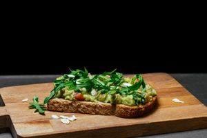 Avocado Toast - open toast of whole bread, guacamole of avocado Hass with tomato brunoise and a fresh onion, rocket and almond flakes  at WellDone Burger in Padua