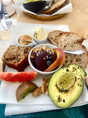 Cake, small açaí bowl, bread, butter, hummus, avocado, fruits and nuts   at Coffee & Waves in Lagos