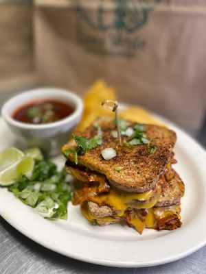 Birria Grilled Cheese Sandwich. Served with corn chips, taco fixings & consomé. at Luna Verde Vegan Mexican Restaurant in Bradley Beach