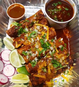 Taquitos Dorados con Consomé de Birria. Crispy Taquitos Dorados with Birria Consomé, drizzled with consomé, queso fundido & shredded, chopped cilantro + onion and taco fixings  at Luna Verde Vegan Mexican Restaurant in Bradley Beach