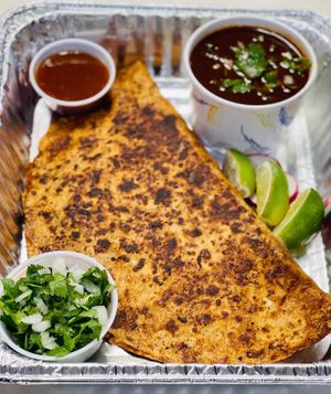 Quesa-Birria quesadilla filled with Birria protien ( No Chivo / seitan or No Puerco/ organic jackfruit). Served with consomé & taco fixings. at Luna Verde Vegan Mexican Restaurant in Bradley Beach