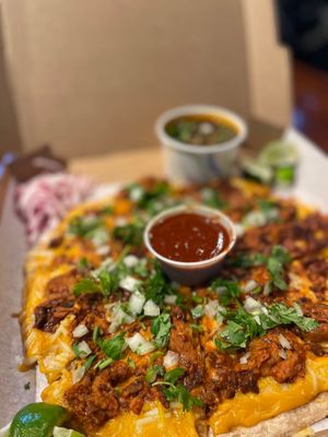 Pizza-Birria quesadilla style pizza, topped with birria protein ( No Chivo / seitan or No Puerco/ organic jackfruit). Served with consomé & taco fixings. at Luna Verde Vegan Mexican Restaurant in Bradley Beach