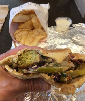 Stuffed Pita Sandwich with hummus, falafel, chopped salad, purple cabbage, sumac onions, Naf pickles, tahini & harissa sauce. Side of Naf fries. at Naf Naf Grill in Bloomington
