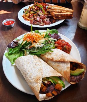 Breakfast burrito with refried beans, tempeh, and avocado, served with a side salad and salsa. In the background...tofu scramble with toast and roasted potatoes. at The Cornerstone in Guelph