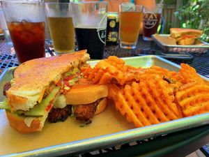 Tempeh grilled cheese with avocado, lettuce, tomatoes and pickles. Waffle fries on the side.  at Golden Dinosaurs in Gulfport