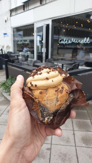Banana peanut butter cupcake with the cafe in the background at Mirells in Visby