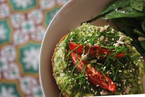 The popular Smash (vegan) Avocado on bagel with basil pesto, roasted tomatoes, spinach, a mix of seeds and side salad. at Inside Cafe in Guanajuato