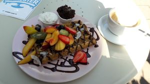 Vegan waffles with coconut cream, plum jam and chocolate sauce (and a flat white). at Cakester Cafe in Krakow