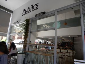 sitting in the outdoor cafe area at Rubik's Superfood & Coffee in Patras
