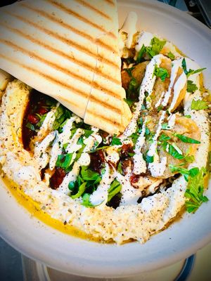 Vegan Shakshuka on a bed of homemade hummus and topped with vegan omelette, fresh parsley, tahini, pomegranate sauce & grilled za'atar bread. Come try it out! at Garbanzo - Falafel & Hummus Bar in Vienna