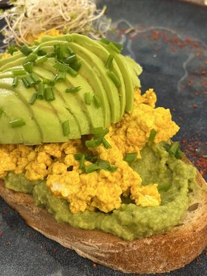 avo toast in detail: tofu scramble, avo spread and a huge portion of avocado on the top, microgreens on the side  at Relax na Wilczej in Warsaw