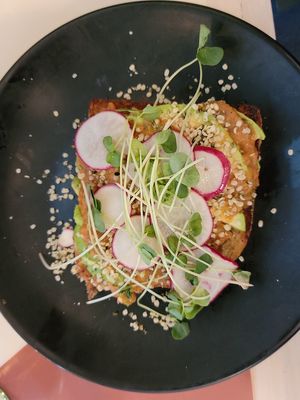 Avocado toast on sourdough toast with tomato chutney, hemp hearts, radish, and salad. at Naive in Louisville