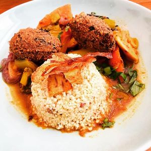 Couscous de pois chiche et légumes (aubergines, céleri branche, carottes, panais, blettes, courge butternut). 
Servi avec millet aux dattes, chips de panais et falafels pois chic at Be Kind Cafe in Geneva