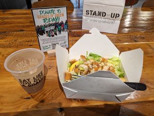 mocha shake and Crispy Chikin Caesar salad in disposable containers in front of sign promoting environmentalism at Stand-Up Burgers in Berkeley