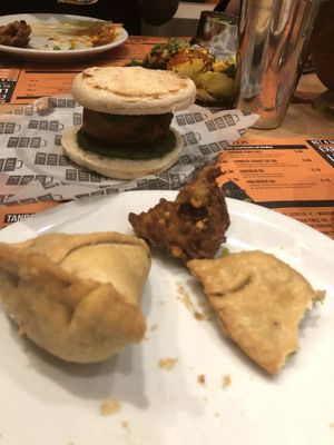 Pea and potato samosas, onion bhaji, and vada pav in the background at Tuk Tuk in Glasgow