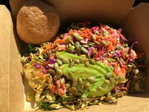 Veggie bowl with kale, quinoa, Brussels sprouts, mushrooms, coleslaw, avocado, Asian dressing, and toasted pumpkin seeds. Rosemary garlic roll on the side.  at Sweet Elizabeth's Organics Bakery in Colorado Springs