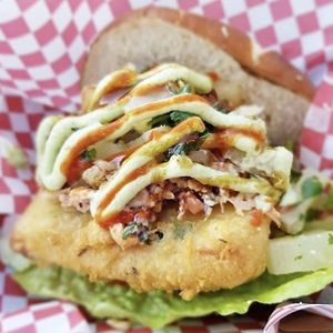 Fish Burger: battered and fried vegan fish topped with tomato, lettuce, coleslaw, pineapple chow, homemade herb mayo, tamarind sauce and chilli sauce, served in a soft pretzel bun at ITIS in East London