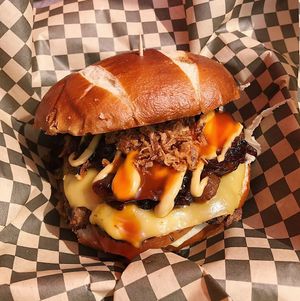 Jerk Burger: homemade ‘beef’ patty marinated in homemade jerk sauce, topped with vegan cheese, lettuce, tomato, caramelised onions, homemade herb mayo and chilli sauce, served in a soft pretzel bun at ITIS in East London