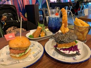 Gammon, egg & pineapple burger (left), tofish stack burger (right), mozzarella sticks (back), chips, and Seaspiracy cocktail  at Unity Diner in East London