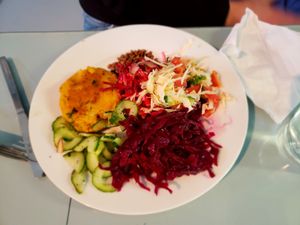 Vegi-burger main dish with salads: cucumbers, fermented (pickled) red cabbage, garden vegetables and toasted sunflower seeds with soy sauce. at The Grove Veggie Kitchen in Limerick