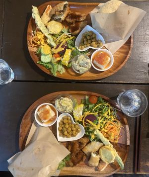 Assiette burger vegan, servie avec un assortiment d’entrées, ici salades, pois chiches, tempura de légumes, tofu frit, et tofu soyeux épicé.  at Ramuna in Nara