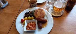 Muffin with vegan egg, arugula, baked beans in tomato sauce, sautéed mushrooms, tomatoes, chickpea sausage, maple mustard dressing, and salad at Palmovka in Prague