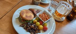 Muffin with vegan cheese, baked beans, grilled tomatoes and mushrooms and chickpea sausages at Palmovka in Prague