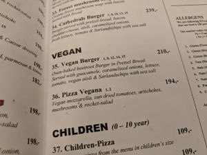 Vegan section of the menu contains a burger and a pizza (May 2019), at Café Cathedral in Oslo