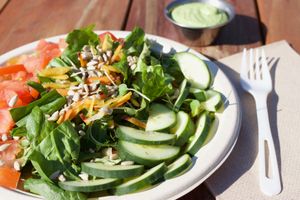 Salad made with spinach, romaine, kale, sprouts, and shredded rainbow carrots topped with sunflower seeds, tomato, and cucumber and dressed with Green Goddess dressing. at The Peaceful Palate in Eugene