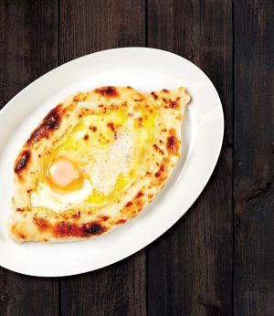 Khachapuri Adzharuli - bread shaped like a boat and filled with melted cheese, raw egg, and butter. at Gruzie in Prague