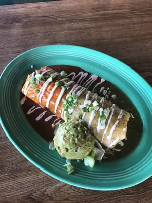 Bandera Burrito. Filled with pinto beans, rice and plant based Chik'n, and pico de gallo. Topped with tomatillo sauce, red enchilada sauce, cashew crema, and green onions. Served with guacamole. at Mi Ranchito in Upland