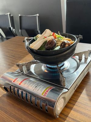 A dumpling and mushroom hot pot. A large cooking pot; filled to the brim. Is placed on a portable gas burner. The burner is lit, and when the broth boils, the hot pot is ready!  at K-pub in Adelaide